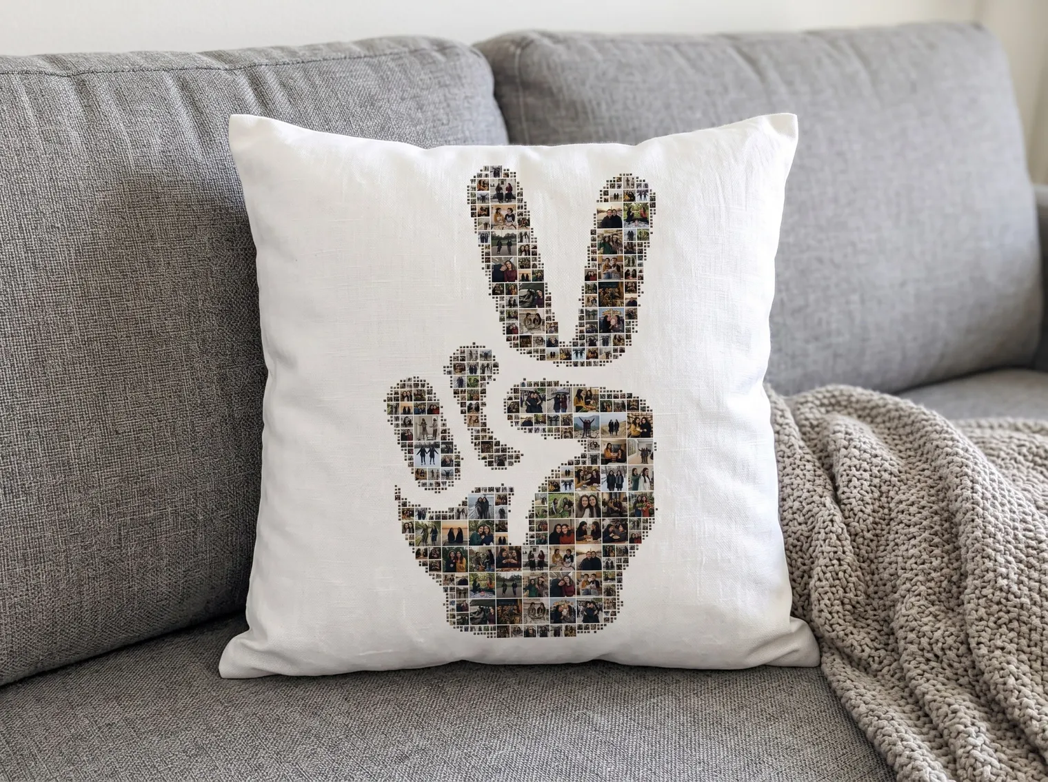 The peace-sign collage printed on a square white linen cushion on a grey sofa